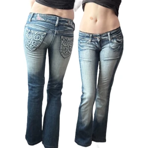 Blå lågmidjade bootcut jeans Crazy Age - Snygga blå lågmidjade bootcut jeans från Crazy Age med snygga detaljer och broderade bakfickor. Jeansen har en klassisk femficksmodell, kontrast sömmar och coolt mönster på bakfickorna. Perfekta för dig som gillar en unik och trendig look.