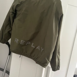 Reversibel bomberjacka från Replay - Säljer en fet reversibel bomberjacka från Replay. Ena sidan är olivgrön med stor logga, andra sidan är röd med galet tiger- och bambumönster. Jackan har dragkedja, resår i midja och ärmar, och är tillverkad i polyester. Perfekt statement-plagg för dig som vill sticka ut. Jackan är lätt fodrad för höst/vår.