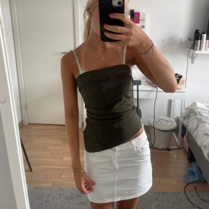 Mörkgrön tubtopp från Gina Tricot XS - Snygg mörkgrön tubtopp från Gina Tricot i storlek XS. Toppen har en enkel och stilren design med rak halsringning och bandeau-form. Tillverkad i mjukt och stretchigt material som sitter tight och bekvämt. Perfekt att matcha med kjol eller jeans för en trendig look.