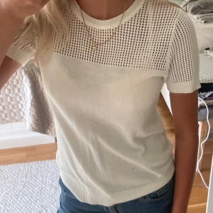 Vit stickad topp från Lindex - Vit stickad topp från Lindex med korta ärmar. Överdelen och ärmarna har ett snyggt hålmönster som gör tröjan lite unik. Materialet är mjukt och stretchigt. Storlek S.