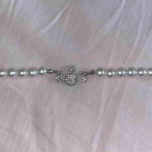 Vivienne Westwood liknande pärlhalsband silver - Ej äkta ‼️ Ikoniskt pärlhalsband som ser exakt ut som Vivienne Westwood med silverfärgat Orb-hänge dekorerat med små glittriga stenar. Halsbandet består av vita pärlor som ger en klassisk men edgy vibe. Perfekt statement piece för att lyfta vilken outfit som helst! 