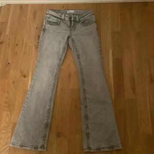 Grå bootcut jeans från Perfect Jeans - Snygga grå jeans från Perfect Jeans i bootcut-modell. Jeansen har en tvättad look, klassiska framfickor och bakfickor med lock och knapp. Tillverkade i mjukt jeanstyg med markerade sömmar och bälteshällor. Perfekta för dig som gillar retrovibbar och stilren design.