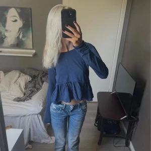 Mörkblå volangtröja med lång ärm - Supersöt mörkblå tröja med volang nertill och långa ärmar. Modellen är lite lös och har en avslappnad passform. Perfekt till jeans för en chill look. Materialet känns mjukt och skönt mot huden.