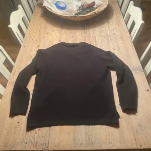 Svart långärmad pikétröja i ull - Säljer en svart långärmad pikétröja från Zara. Tröjan har klassisk krage och knäppning vid halsen. Tillverkad i mjuk ull. Perfekt för en stilren och enkel look. storlek:S