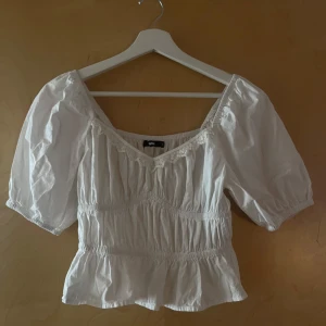Vit blus med spets från BikBok - Supersöt vit blus från BikBok i storlek S med puffiga korta ärmar💕säljer pågrund av att den inte kommer till användning och har aldrig andvänt💘 skriv för frågor eller mer bilder💋