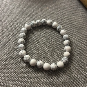 Vitt pärlarmband med marmormönster - Snyggt armband med runda vita pärlor och grått marmormönster. Elastisk tråd gör det enkelt att ta på och av. Perfekt accessoar för att ge din outfit en clean och trendig touch.