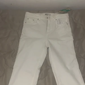 Offwhite kick flare jeans från Gina Tricot - Snygga offwhite kick flare jeans från Gina Tricot i modellen Nicole. Byxorna har klassisk femficksdesign, hög midja och utsvängda ben med råa kanter nertill. Perfekta för dig som vill ha en fräsch och trendig look.