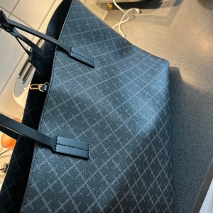 Maline Birger väska - Säljer min stilrena skolväska från Malene Birger i klassisk svart färg. Den har använts i ca 3 månader och är i mycket fint skick! Alla band, dragkedjor och detaljer är hela och fungerar perfekt.  📍Skick: Nästan som ny 📍Användning: Ca 3 månader 📍Färg: Svart 📍Märke: Malene Birger 📍Övrigt: Det finns några små fläckar inuti väskan som lätt kan tvättas bort – inget som påverkar användningen.  Perfekt som skolväska, datorväska eller vardagsväska – rymlig, snygg och praktisk!