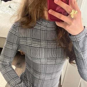 Rutig långärmad bodysuit Fashion Nova - Säljer en svartvit rutig bodysuit från Fashion Nova med lång ärm och hög hals. Tight passform och stretchigt material som sitter snyggt på kroppen. Står ej storlek på men skulle säga att den sitter som en xs💗