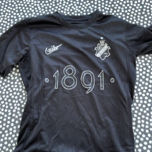  AIK tröja ”smoking lirare” - AIK fotbollströja i svart från Nike med klubbmärke och årtalet 1891 tryckt på bröstet. Tröjan har korta ärmar, rund hals och texten 'SMOKINGLIRARE' i nacken. Limited edtion