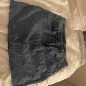 Low waist jeanskjol - Snygg blå jeanskjol med  bakfickor och bälteshällor. Kjolen har en rak passform och rå, avklippt kant nertill för en cool vibe. Går såklart att klippa mer om man vill!! 