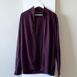 Bugatti vinröd kofta jacka med kashmir  - Ny och oanvänd vinröd zip-tröja från Bugatti. Passar perfekt som en lätt jacka på kvällen eller som en varm tröja inomhus. Bomull 95% Kashmir 5%. Nypris 1000kr.