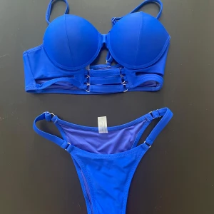 Blå bikini från Fashion Nova, S - Galet snygg koboltblå bikini från Fashion Nova med vadderad bygel-bh och justerbara axelband. Underdelen har lågt skuren modell och smala sidor med metallringar. Tillverkad i stretchig polyester och elastan för perfekt passform. Står storlek s men tycker överdelen är mer m och underdelen mer åt xs!