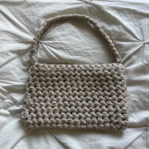 Beige virkad axelväska - Säljer en handgjord beige axelväska med chunky stickad look och flätat axelband. Perfekt storlek för mobilen och det viktigaste. 