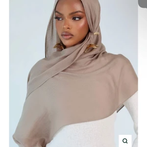 KLAYTHELABEL PREMIUM MODAL rhassoul  - KLAY THE LABEL PREMIUM MODAL HIJAB I FÄRGEN RHASSOUL. Stilren beige hijab med snygga guldfärgade detaljer på sidan. Tunt och lätt material som faller snyggt över axlarna. Perfekt för dig som vill ha en enkel men elegant look. Helt ny och inte öppnad, säljer för att jag har två stycken och den kommer inte till användning. En undercap i samma färg följer med!!