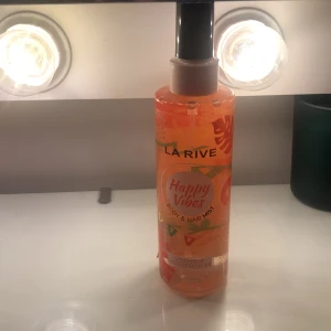 La Rive Happy Vibes Body & Hair Mist - Fräsch body & hair mist från La Rive i doften Happy Vibes. Flaskan är orange med färgglada detaljer och rymmer 200 ml. Innehåller vitamin E och provitamin B5 för extra vård. Perfekt för dig som vill ha en lätt och uppfriskande doft till både kropp och hår.