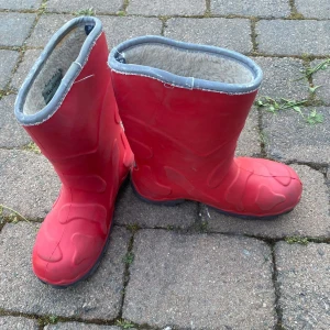 Röda fodrade stövlar från Navigator - Säljer ett par röda stövlar från Navigator med grå kant och mjukt foder på insidan. Stövlarna har en cool, mönstrad yta och är perfekta för kalla och blöta dagar. Sula i svart och rund tå för skön passform.