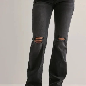 Svarta bootcut jeans med slitningar - Snygga svarta lågmidjade jeans med bootcut passform och slitna hål över knäna. Helt nya från Nelly! Slutsålda i denna storlek. 699kr nypris! Pris går att diskuteras.