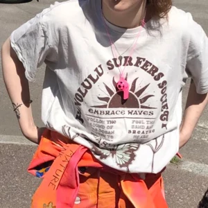 Vit t-shirt med tryck Honolulu Surfers - Säljer en vit t-shirt med brunt retrotryck. Tyvärr hade jag ingen bättre bild men ryggen är helvit och tröjan har en ljusblå fjäril längre ner på magen.