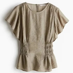 Beige blus med volangärm - Snygg beige blus med korta volangärmar och smockdetaljer i midjan som ger en feminin siluett. Tillverkad i ett lätt och luftigt material, perfekt för varmare dagar. Rund halsringning och avslappnad passform. oppss min är ifrån Shein och väldigt lik på bilden! 