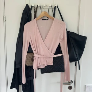 Ljusrosa omlottopp med knytband - Supersöt ljusrosa omlottopp från lager med långa ärmar och knytband i midjan. 