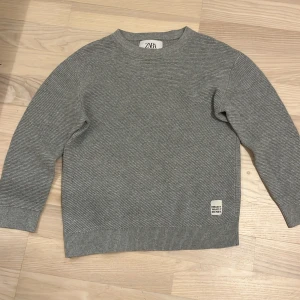 Grå ribbad tröja från Zara - Säljer en grå ribbad tröja från Zara i storlek 122. Tröjan har rund halsringning och långa ärmar.