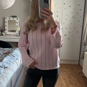 Ljusrosa stickad tröja med hålmönster - Superfin ljusrosa stickad tröja med diskreta hål i lodräta rader. Tröjan har en avslappnad passform och långa ärmar, perfekt för dig som gillar en söt och enkel stil. Passar till både jeans och kjol.