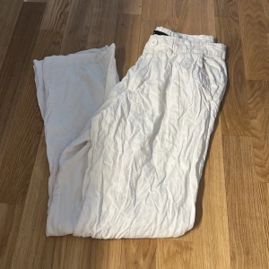 Vita linnebyxor med avslappnad passform - Snygga vita linnebyxor med rak och loose passform. Byxorna har sidfickor och stängs med knapp och dragkedja. Perfekta för varma dagar när du vill ha en chill och stilren look.