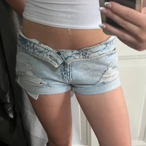 Lågmidjade ljusblå jeansshorts &Denim - Lågmidjade ljusblå jeansshorts från &Denim i storlek 36. De har slitna detaljer och råa kanter, samt en cool tvättad look med vikta benslut. Perfekta för en avslappnad och trendig stil i sommar💗