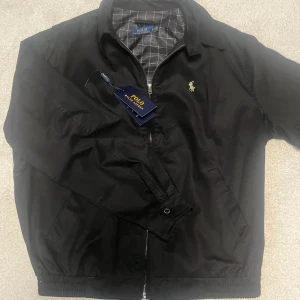 Polo kofta/ tunnjacka  - En svart och fin tunn jacka/ kofta från polo raulph lauren. Har knappt använt den på grund av att den är för stor. Den är i storlek M och finns inga skador eller fläckar, skickas med tag och påsen. Skriv vid någon fundering✅🙌