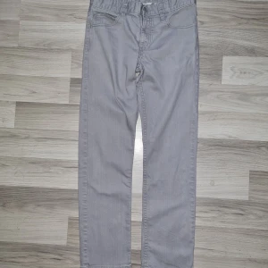 Grå jeansbyxor från H&M, storlek 164 - Snygga grå jeansbyxor från H&M i storlek 164. Klassisk femficksmodell med knapp och dragkedja framtill. Byxorna har raka ben och är tillverkade i ett mjukt bomullsmaterial som är skönt att bära hela dagen.