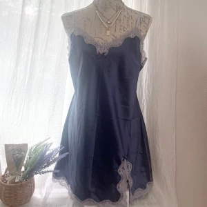 Mörkblå spetsklänning Victoria's Secret - Supersöt mörkblå kortklänning från Victoria's Secret med tunna axelband och ljus spets längs urringning och fåll. Passar storlek M-L.