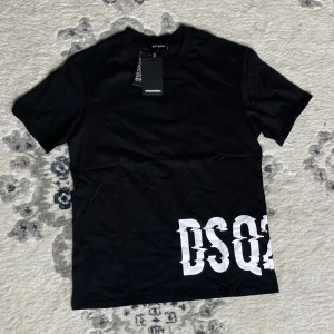 Svart DSQUARED2 t-shirt med tryck - Svart t-shirt från DSQUARED2 i bomull med stort vitt DSQ-tryck nertill på framsidan. Klassisk rund halsringning och korta ärmar. Snygg och stilren modell som passar perfekt till jeans eller shorts.