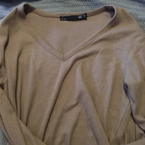 Beige ribbad långärmad tröja V-ringad - Säljer en beige ribbad långärmad tröja från 157 med snygg v-ringning. Perfekt basic-plagg med skön passform och stretchigt material. Enkel att styla till olika outfits och passar året runt.