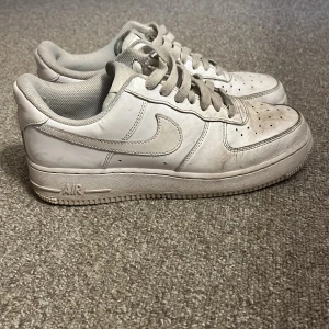 Vita Nike Air Force 1 sneakers - Klassiska vita Nike Air Force 1 sneakers i skinn med rund tå och snörning. Snygg och tidlös modell med låg profil och perforerade detaljer på tån för extra ventilation. Perfekta för dig som gillar streetstyle och vill ha en ikonisk sneaker i garderoben. Har ej tvättat dem på bilderna men skriv till mig för bättre bilder.