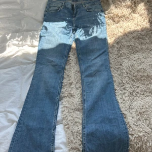 Blå bootcut jeans från Zara - Snygga blå bootcut jeans från Zara med klassisk femficksmodell och lätt slitna kanter nertill. Jeansen har normal midja och är gjorda i mjukt denimtyg som sitter skönt. Perfekta för dig som vill ha ett par jeans med lite extra vidd nedtill.