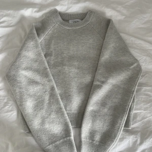 Ljusgrå sweatshirt från Zara - En stilren ljusgrå sweatshirt från Zara med rund hals och ribbade muddar. Tröjan har en klassisk passform och är perfekt att matcha med jeans eller joggers. Mjuk och skön, passar dig som gillar enkel och clean stil.