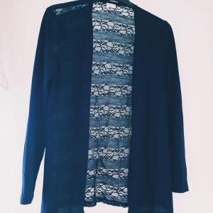 Jacqueline de yong Marinblå cardigan kofta i spets strl S - Snygg marinblå cardigan jacka från Jacqueline de Yong i spetsmaterial. Jackan är långärmad, öppen framtill och har ett genomgående spetsmönster som ger en cool och luftig vibe. Perfekt att slänga över en topp för en extra touch.  Helt skick dock nopprig