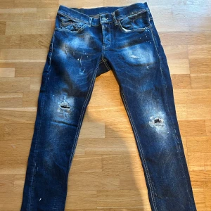 Blå skinny jeans från George, stl 31 - Säljer ett par blå skinny jeans från George i storlek 31. Jeansen har slitna detaljer, hål på benen och coola färgstänk för en riktigt edgy look. Klassisk femficksmodell med dragkedja och knapp. Givetvis autentiska använda ca 10 gånger 
