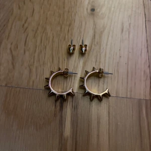 Guldiga örhängen med spikes - Två par coola örhängen i guldton, ett par hoops med utstickande spikes och ett par små studs med spetsig form. Perfekt för dig som gillar edgy och unik stil. Säljs som set och passar till att lyfta vilken outfit som helst.