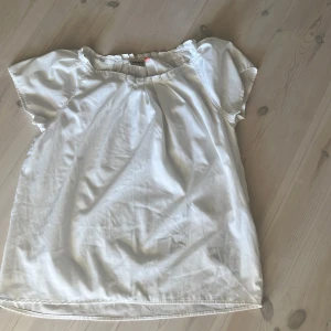 Vit blus från ONLY med kort ärm - Säljer en luftig vit blus från ONLY i storlek 36. Blusen har korta ärmar, rundad hals med lätt rynk och avslappnad passform. Perfekt till jeans eller kjol för en fräsch look. Materialet känns mjukt och lätt mot huden.