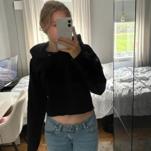 Svart hoodie med huva - Svart hoodie med huva och långa ärmar. Tröjan har en enkel design utan synliga mönster eller detaljer, perfekt för en chill och avslappnad stil. Passformen är loose och materialet känns mjukt och bekvämt mot huden.