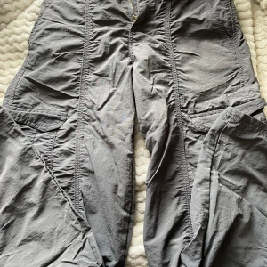Grå cargopants från H&M, strl 152 - Säljer ett par grå cargopants från H&M i storlek 152. Byxorna, stora fickor på sidorna och är tillverkade i lätt polyester. Perfekt för dig som gillar en chill och praktisk stil med mycket rörelsefrihet.