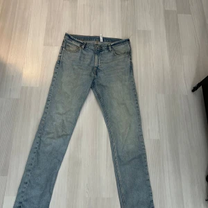Weekday Sunday Slim Jeans ljusblå - Slimmade ljusblå jeans från Weekday, modellen Sunday Slim Jeans. Klassisk femficksdesign med knapp och dragkedja i midjan. Jeansen har en rak och smal passform, tillverkade i mjukt bomullsmaterial med snygga slitningar för en chill vibe.