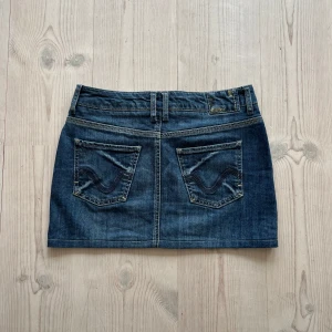 Blå lågmidjad jeanskjol  - Blå lågmidjad jeanskjol från Esprit i fint skick. Kan inte hitta storlek men skulle säga S, kanske passar M också. Tvärs över midjan är det 38 cm och den är ca 33 cm lång (längs med sidan). Använd gärna köp nu!