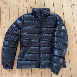 Svart Moncler Jacka Kvinna ”Bady” - Svart moncler jacka, storlek 3 (W). Äkthetscertifikat finns! Tvivla inte på frågor eller dylikt. Väldigt fint skick! Perfekt jacka till hösten, vintern och våren! Modell ”Bady”, luvan saknas.