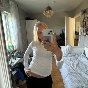 Vit långärmad topp i bomull - Säljer en enkel och fräsch vit långärmad topp i mjuk bomull. Modellen är slim och sitter snyggt mot kroppen, perfekt att styla med jeans eller kjol. Klassisk rund hals och utan synliga detaljer. Passar dig som gillar clean och stilren look. Lite kort i armarna. Strl 150 men sitter som xxs.