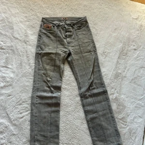 Grå jeansbyxor från Corteiz - Säljer ett par grå jeansbyxor från Corteiz med coola broderade stjärnor på bakfickorna och en unik läderpatch fram. Byxorna har raka ben, knappgylf och tydliga sömmar längs benen. Materialet är klassisk jeans och passformen är normal.