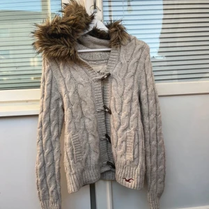 Hollister kofta - Supersnygg kofta från Hollister, kabelstickad med päls💖 I bra skick, lite smutsig och nopprig men inget som påverkar användning!😇 Jag är 160 o tycker den är liten i storlek!💖