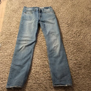 Tiger of Sweden ljusblå jeans Meg 27/32 - Säljer ett par ljusblå jeans från Tiger of Sweden, modell Meg. De har klassisk femficksdesign, raka ben och normal passform. Jeansen är tillverkade i bomull och har snygga slitningar för en cool look. Perfekt för dig som gillar stilrena och tidlösa jeans.